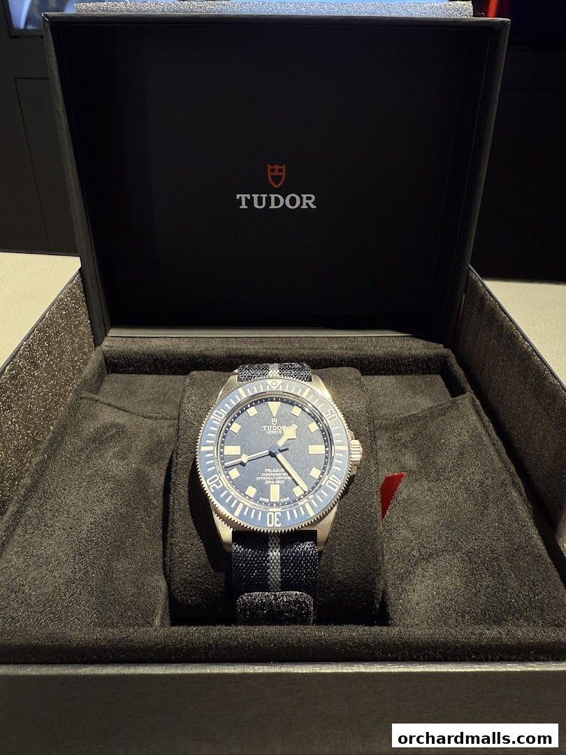 A Tudor Pelagos watch with a blue dial and fabric strap in its presentation box.