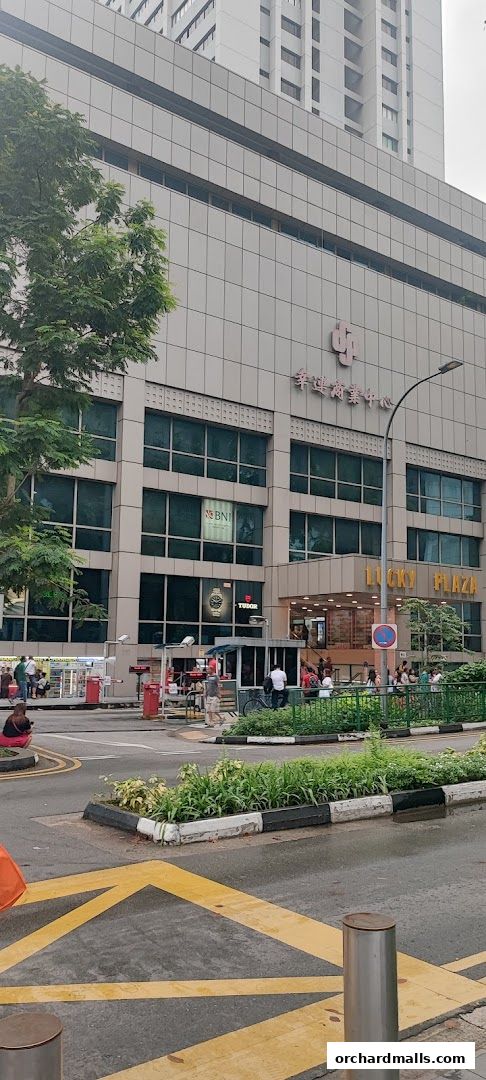 Exterior view of Lucky Plaza building with a Tudor watch advertisement.