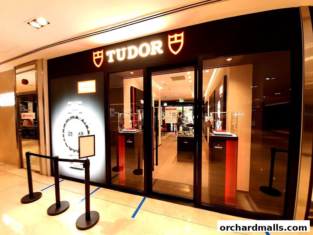 The exterior of a Tudor watch shop with a large display and glass doors.