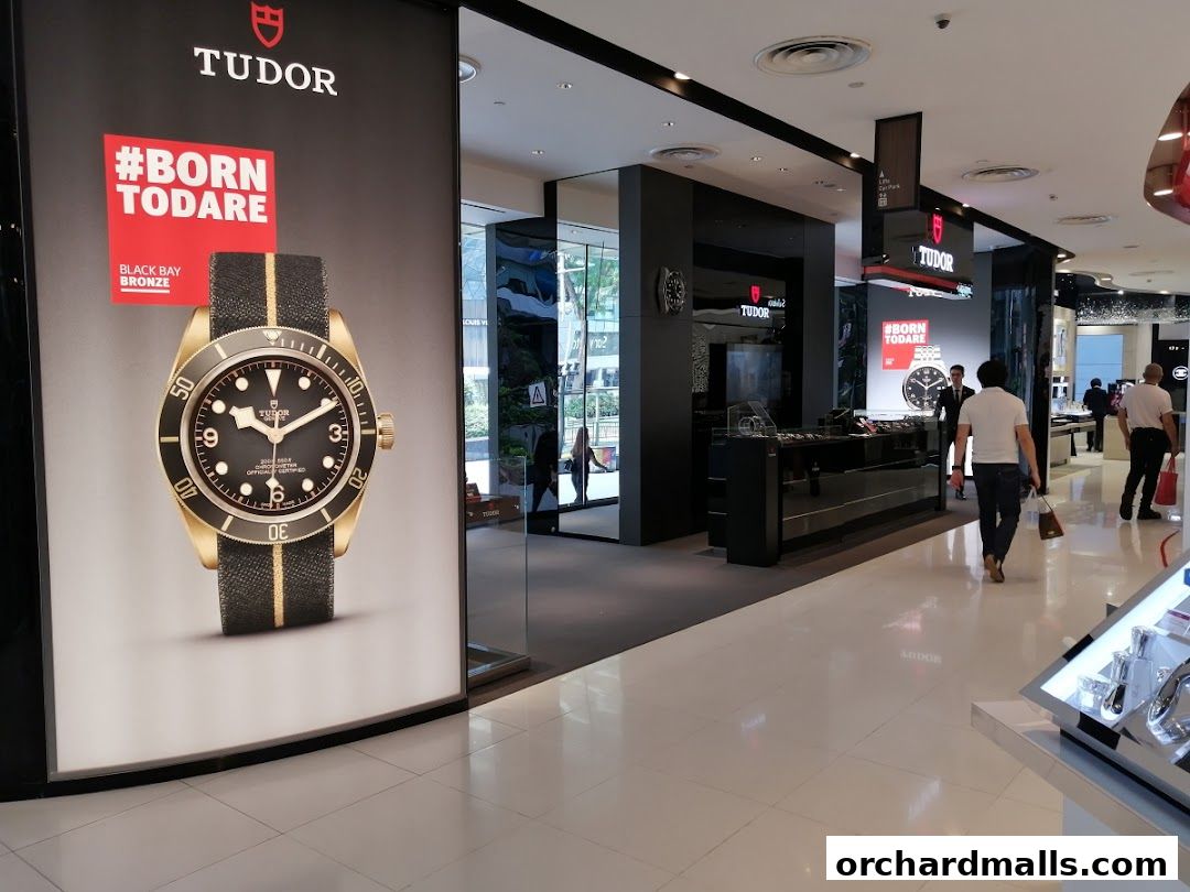 Exterior view of a Tudor watch shop with a large advertisement for a bronze watch.