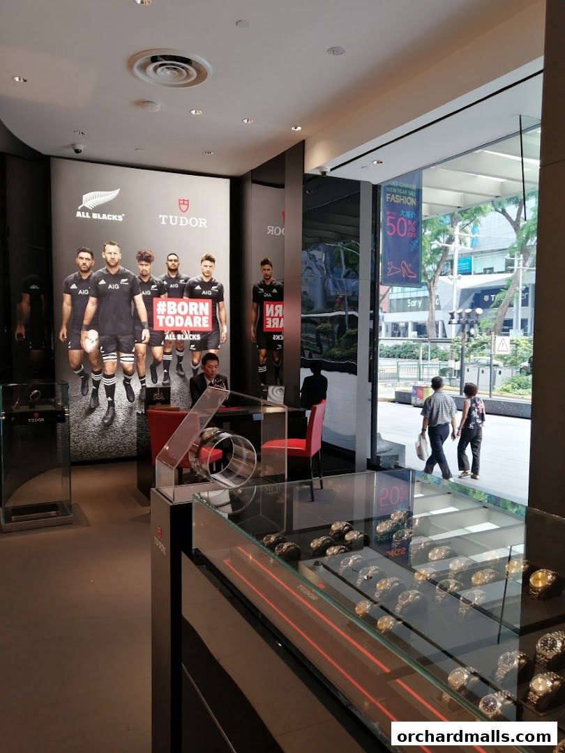 Interior of a Tudor watch shop with displays of watches and a promotional poster.