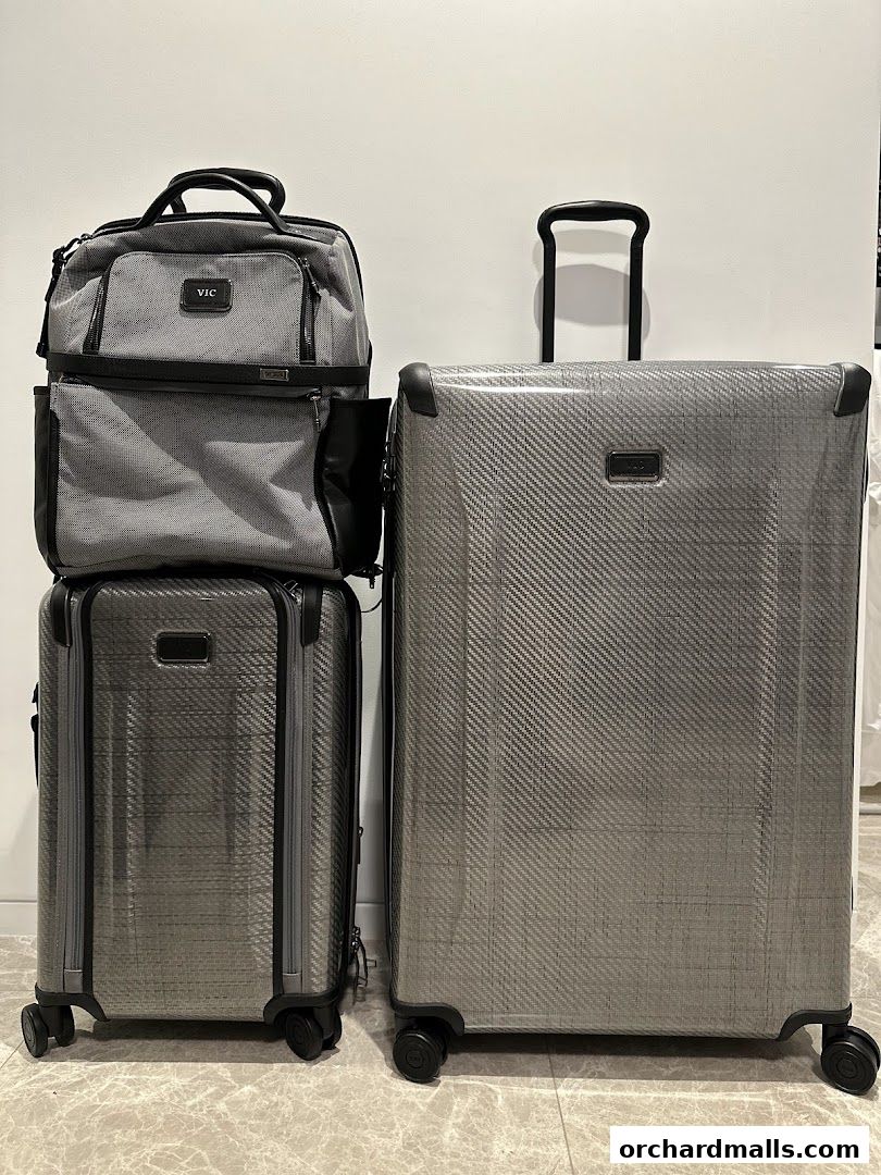 A collection of stylish grey TUMI luggage, including a carry-on and a larger suitcase.