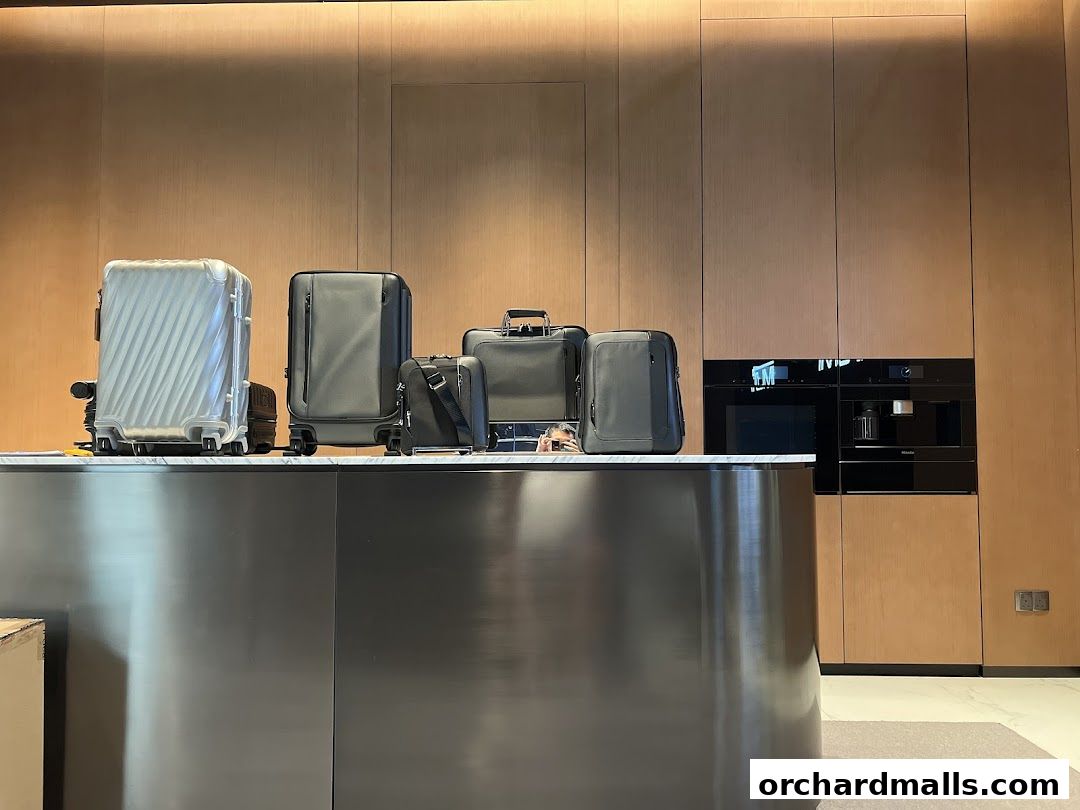 A display of TUMI luggage and travel accessories on a counter with a modern kitchen appliance in the background.