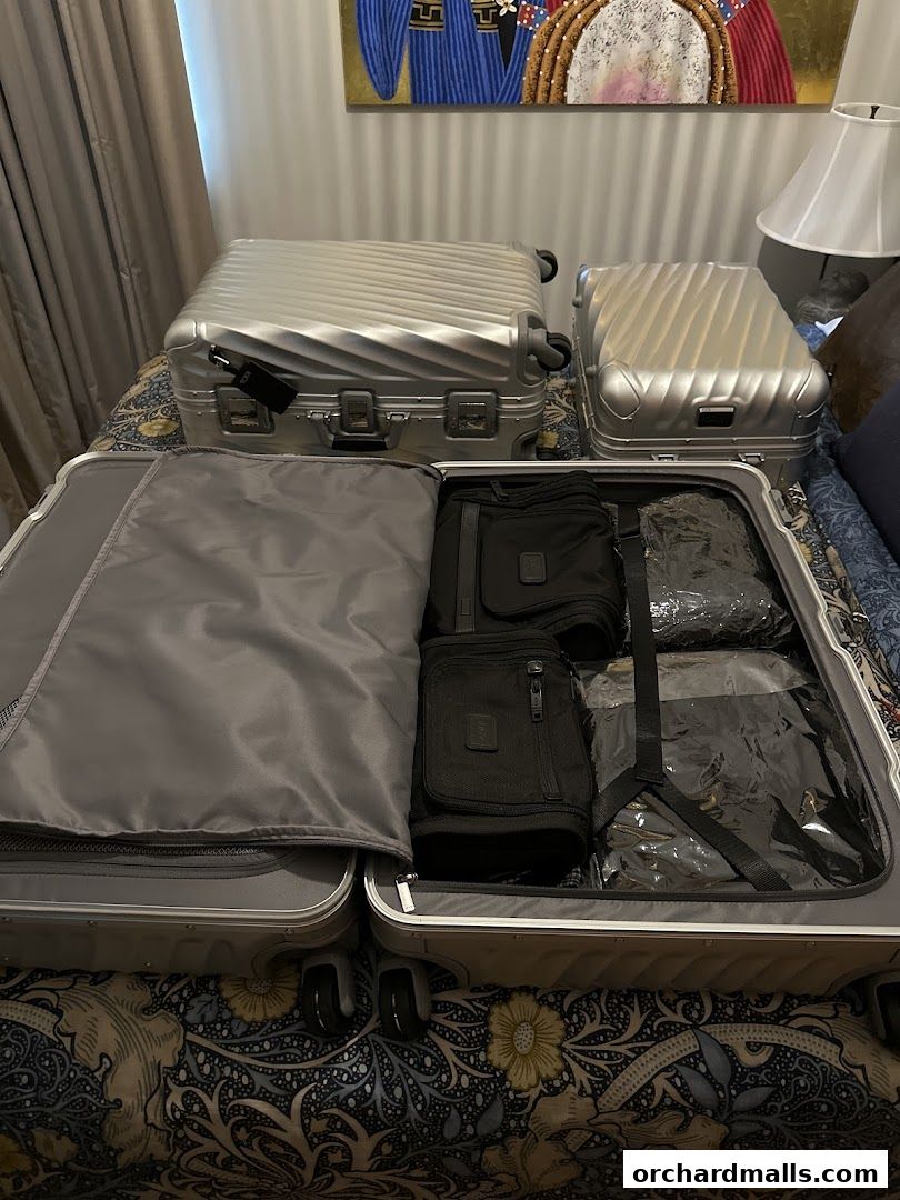 Two silver TUMI suitcases are packed with travel accessories and organized with packing cubes.