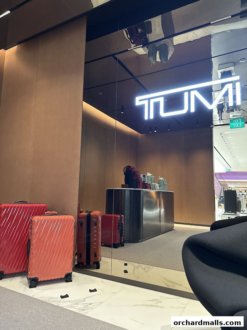 The TUMI store entrance displays colorful luggage and the illuminated TUMI logo.