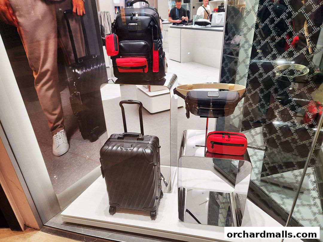A TUMI store window display featuring various luggage and bags, including a backpack and suitcases.