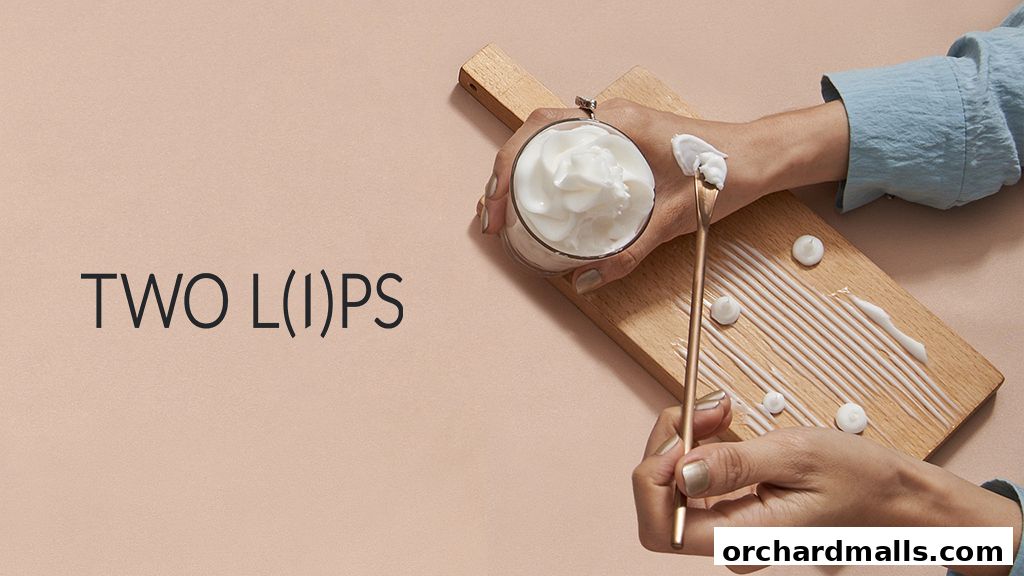 Hands applying cream from a jar onto a wooden board with a spatula.