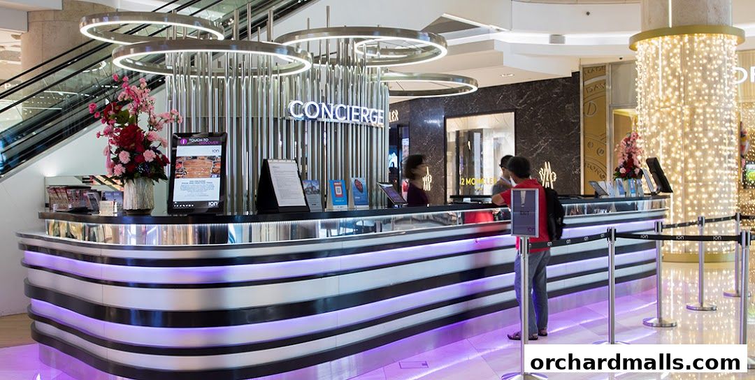 A modern concierge desk with floral arrangements and digital displays in a shopping mall.
