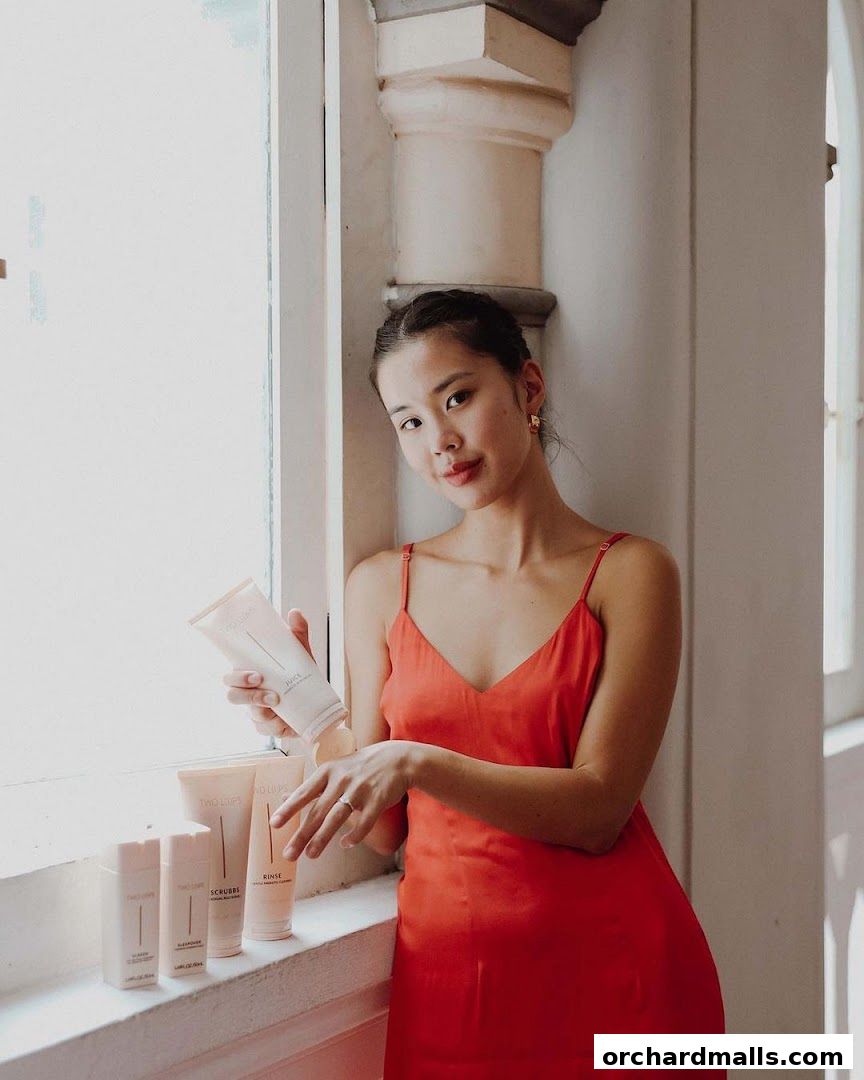 A woman in a red dress holds skincare products from TWO LIPS.
