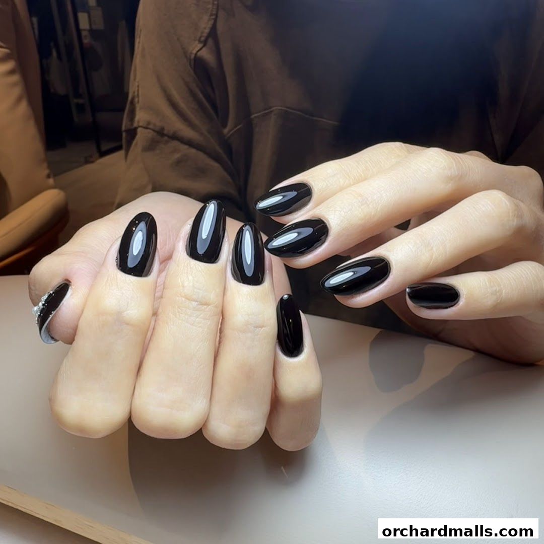 Close-up of hands with glossy, black almond-shaped nails.