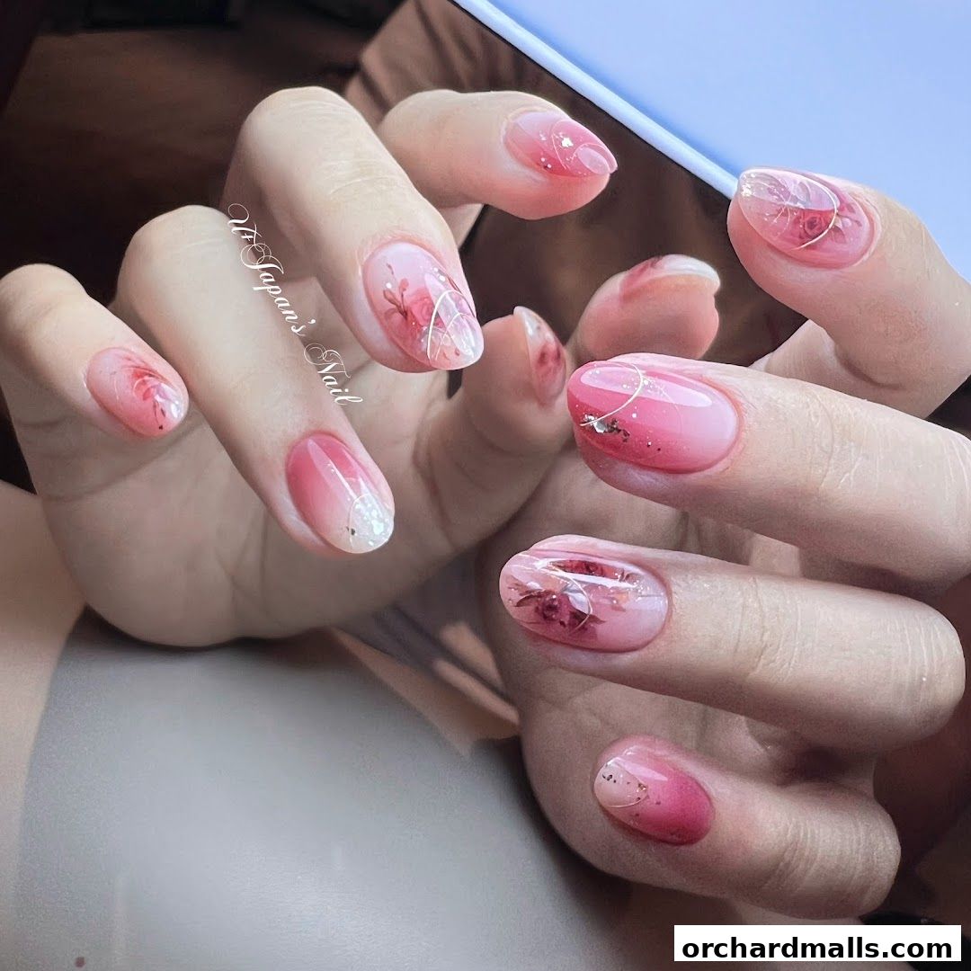Close-up of hands with beautifully decorated pink gradient nails featuring floral designs.