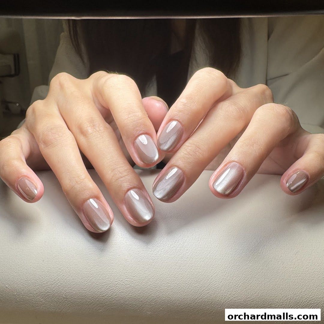 Close-up of hands with elegant, neutral-toned gel manicures.