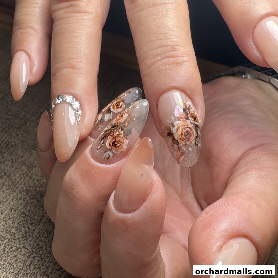 Close-up of hands with elegant nude and floral-designed acrylic nails.