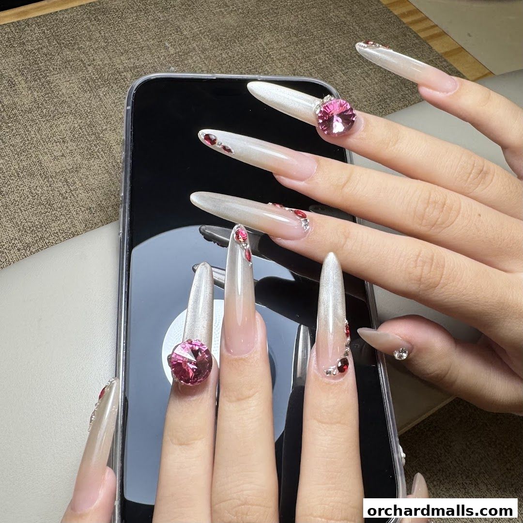 Close-up of hands with long, ornate nails adorned with gems and rhinestones.