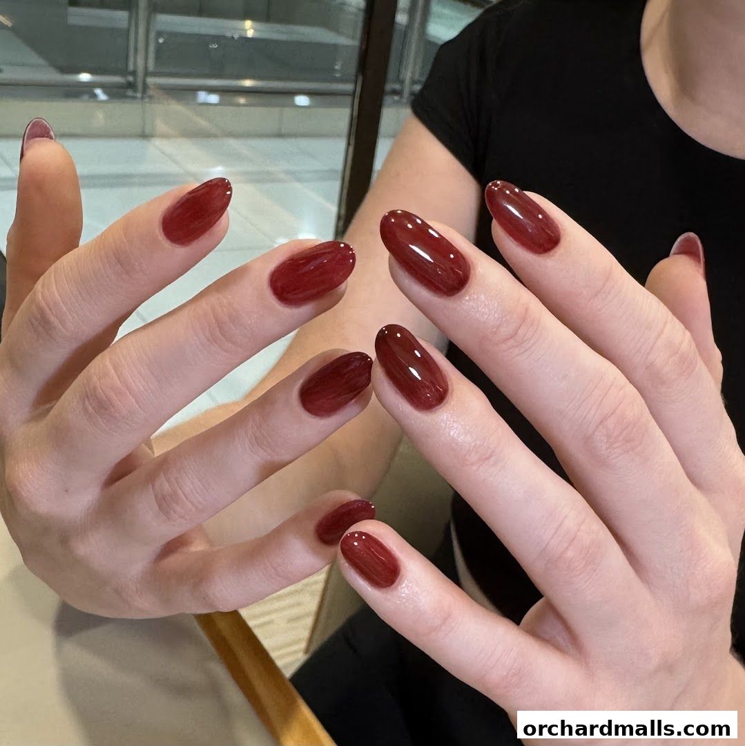 Close-up of hands with glossy, deep red gel manicured nails.