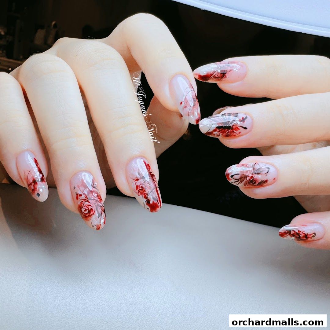 Close-up of hands with intricate floral nail art featuring red roses and delicate lines.
