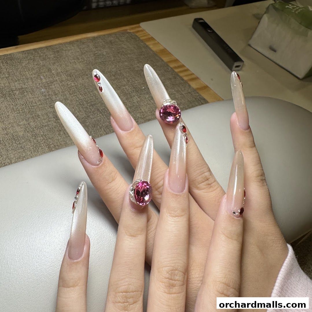 Close-up of hands with long, ornate acrylic nails adorned with gems.
