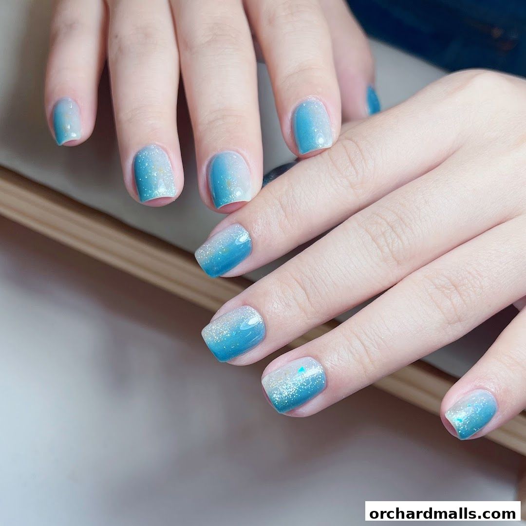 Close-up of hands with beautiful blue ombre and glitter nail art.