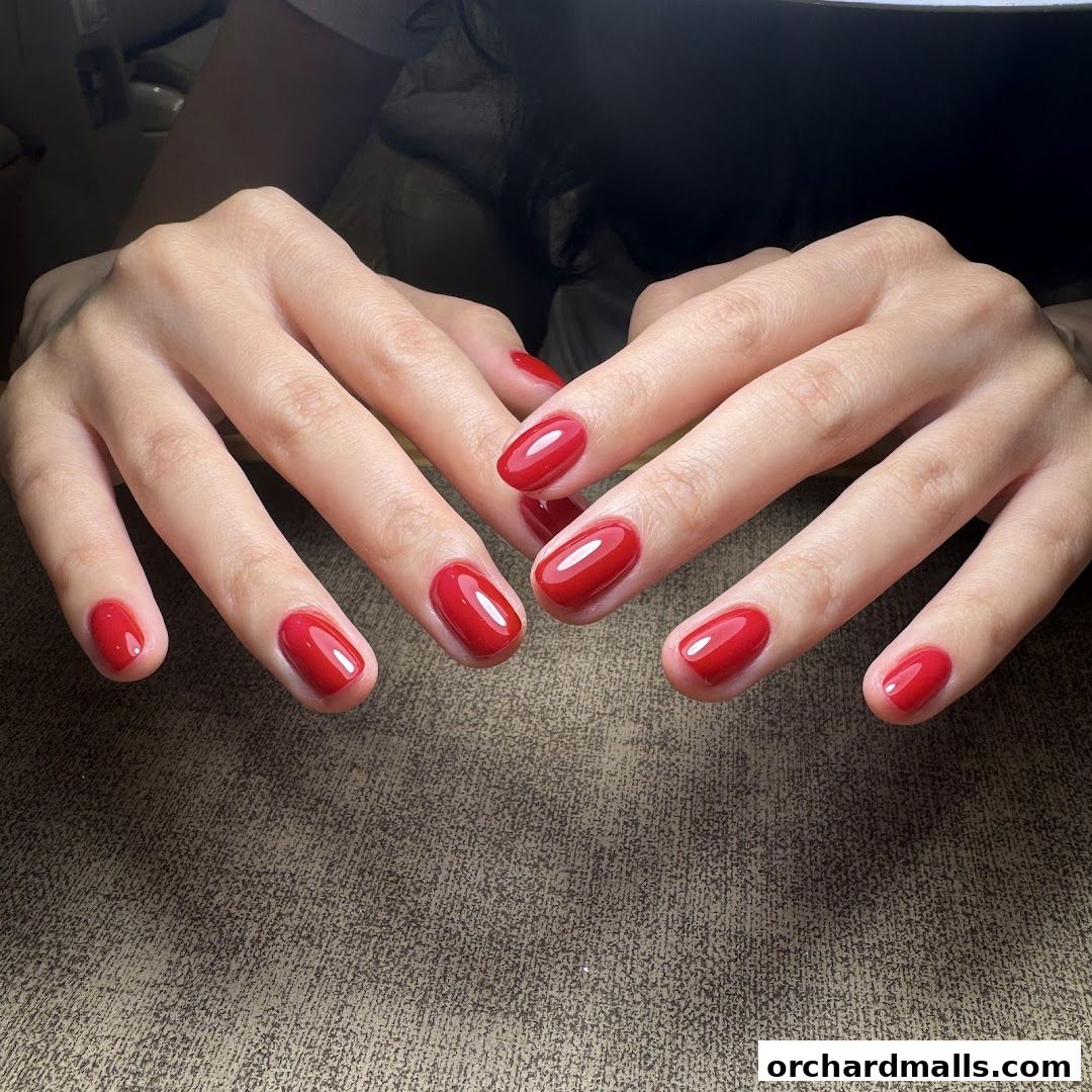 A close-up shot of hands with perfectly manicured, glossy red nails.
