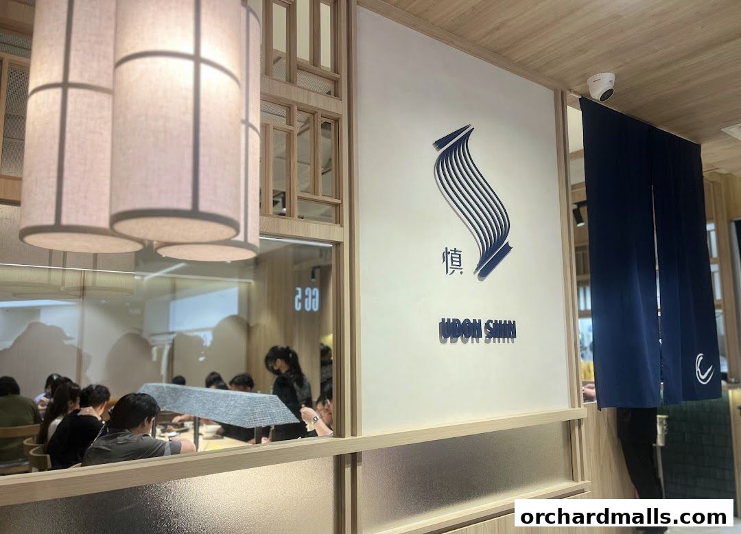 Interior view of Udon Shin Singapore restaurant with logo and diners.