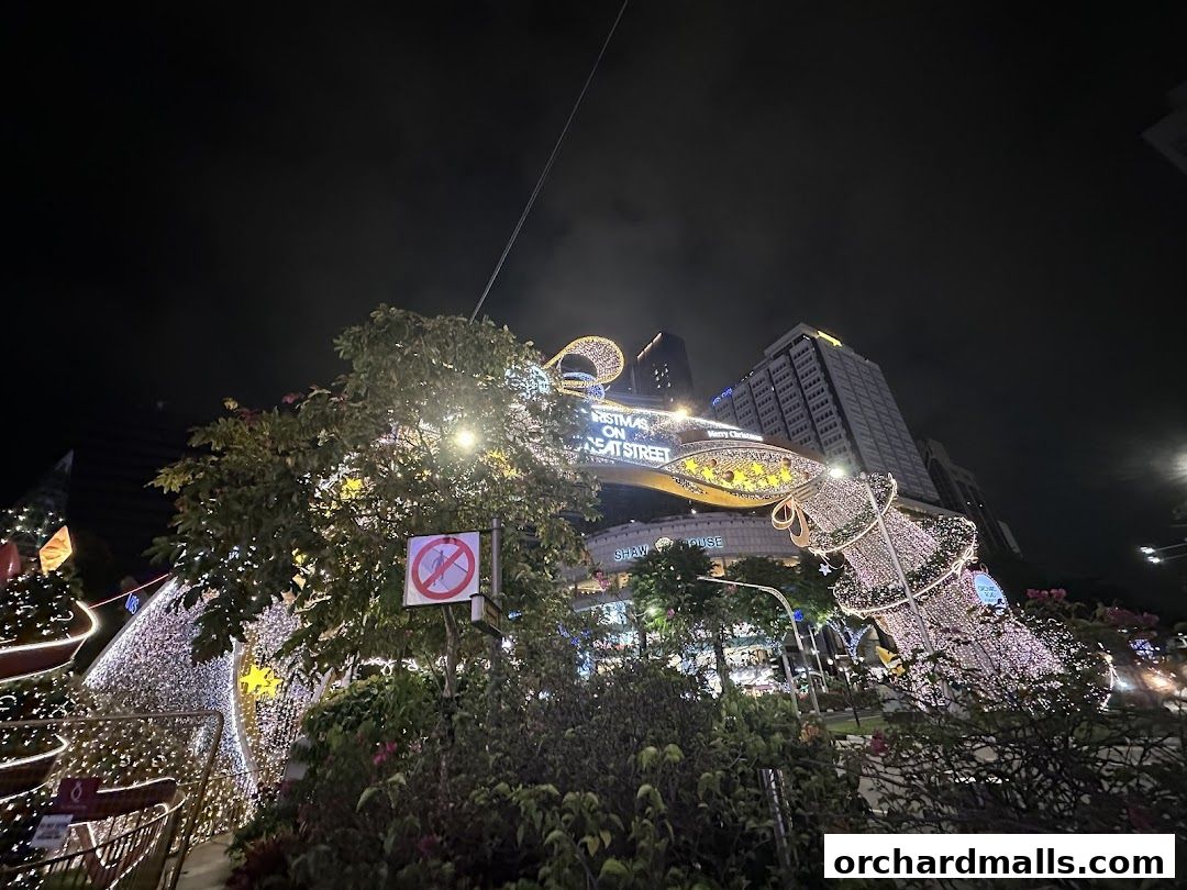 Night view of a street decorated with Christmas lights and a large bell.