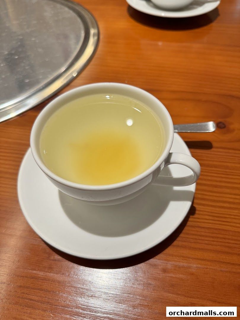 A close-up shot of a white cup filled with a light-colored beverage on a saucer.