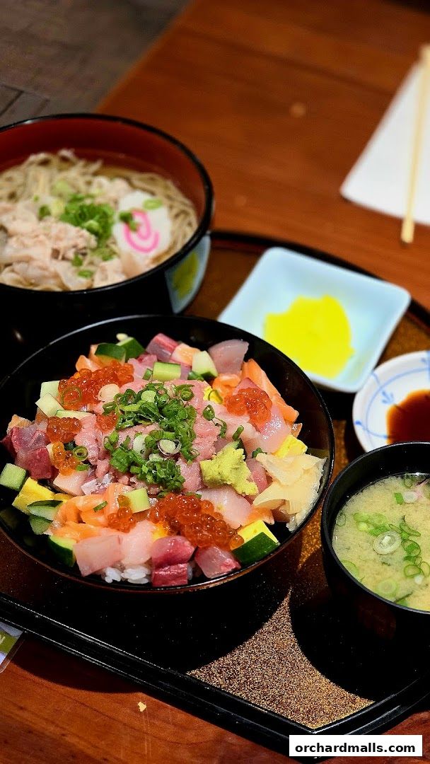 A delicious chirashi bowl with fresh sashimi, ikura, and vegetables, served with soba and miso soup.