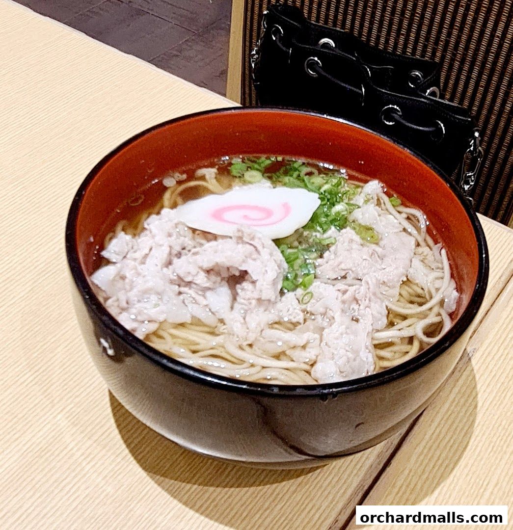 A close-up of a steaming bowl of ramen with pork and narutomaki.