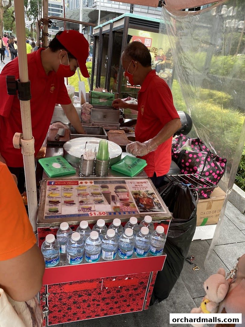 Two vendors in red shirts prepare traditional wafer ice cream at a street stall.