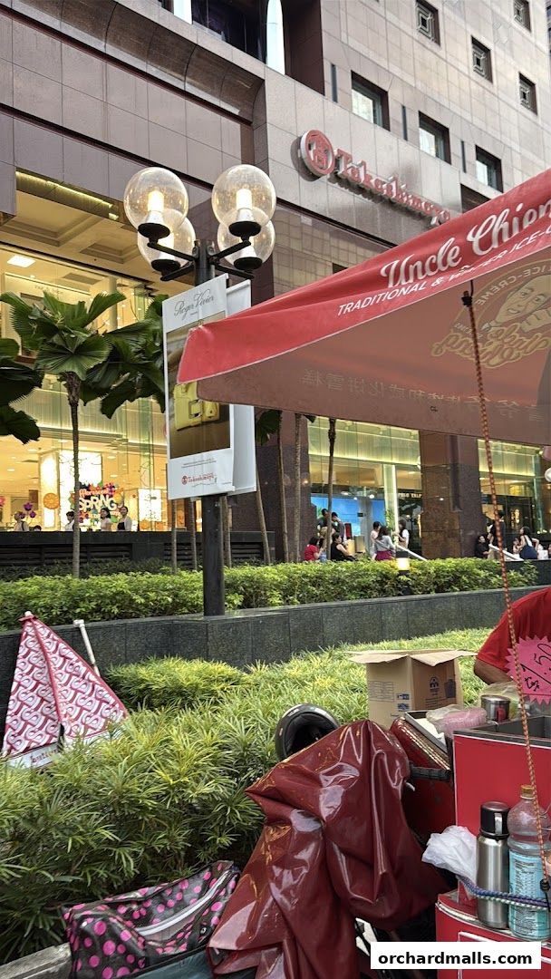 A street vendor stall with a red awning, selling traditional wafer ice cream.