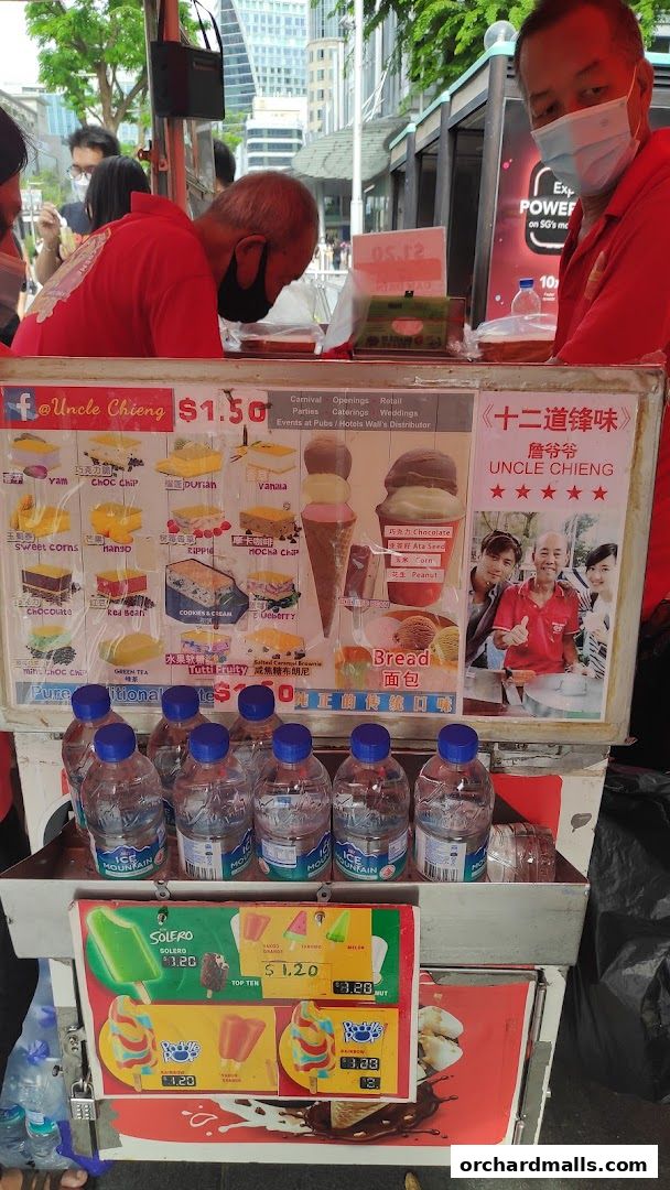 A street vendor cart displaying a variety of ice cream flavors and popsicles with prices.