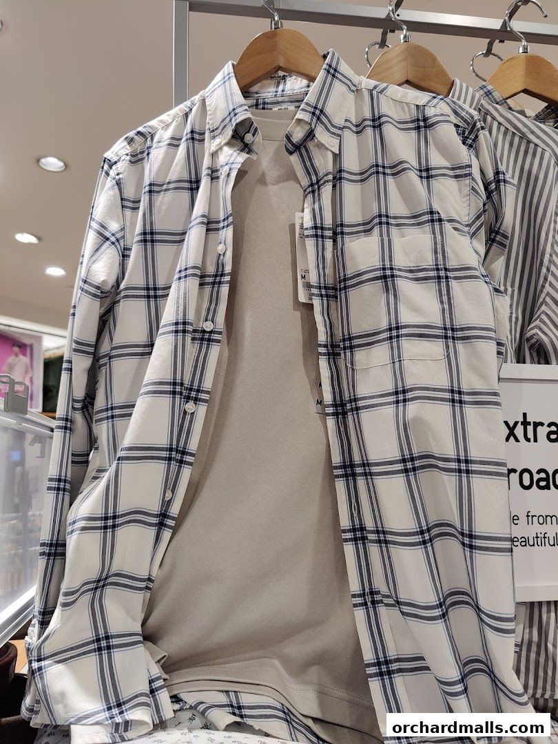 A close-up view of plaid shirts and a t-shirt on hangers in a retail store.