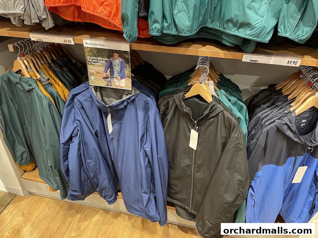 A display of colorful Uniqlo parkas on hangers, featuring a promotional sign.