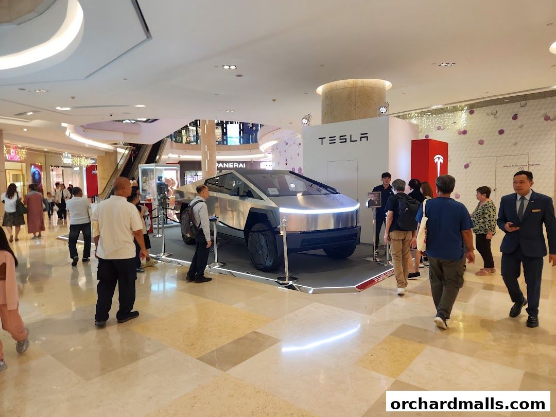 A Tesla Cybertruck is on display in a shopping mall with people looking at it.