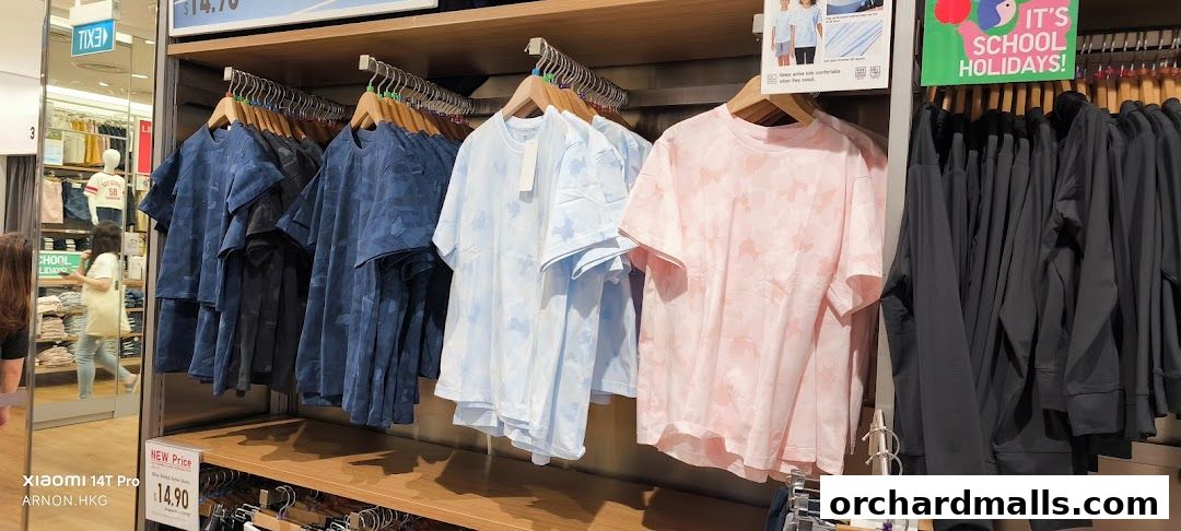 A display of colorful t-shirts and dark jackets on hangers inside a UNIQLO store.