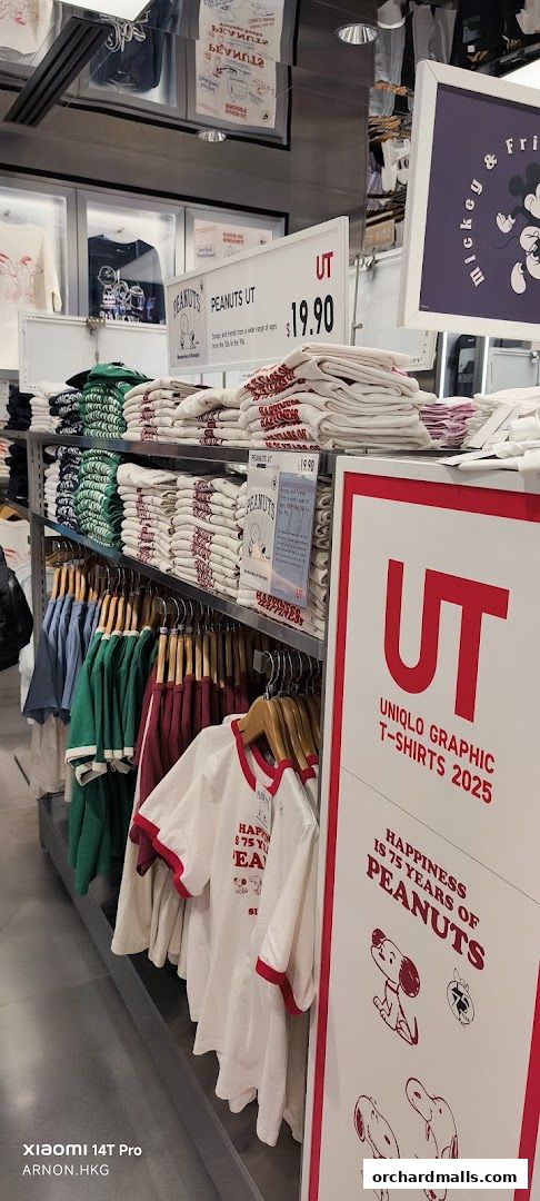 A display of UNIQLO graphic t-shirts featuring Peanuts and Mickey & Friends designs.