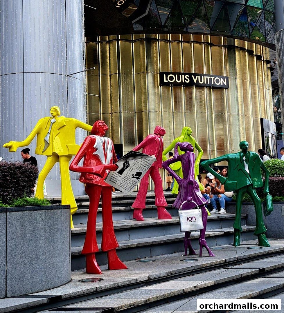 Colorful sculptures of people in front of a Louis Vuitton store.