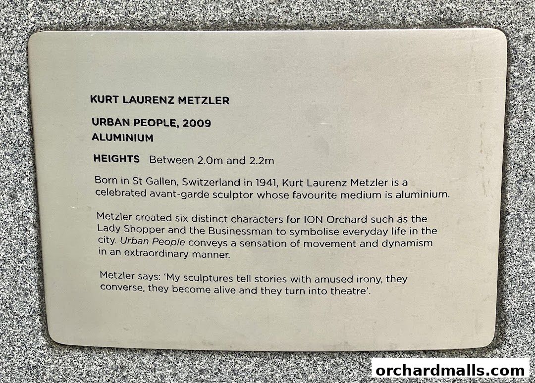 A plaque detailing information about the 'Urban People' sculpture by Kurt Laurenz Metzler.
