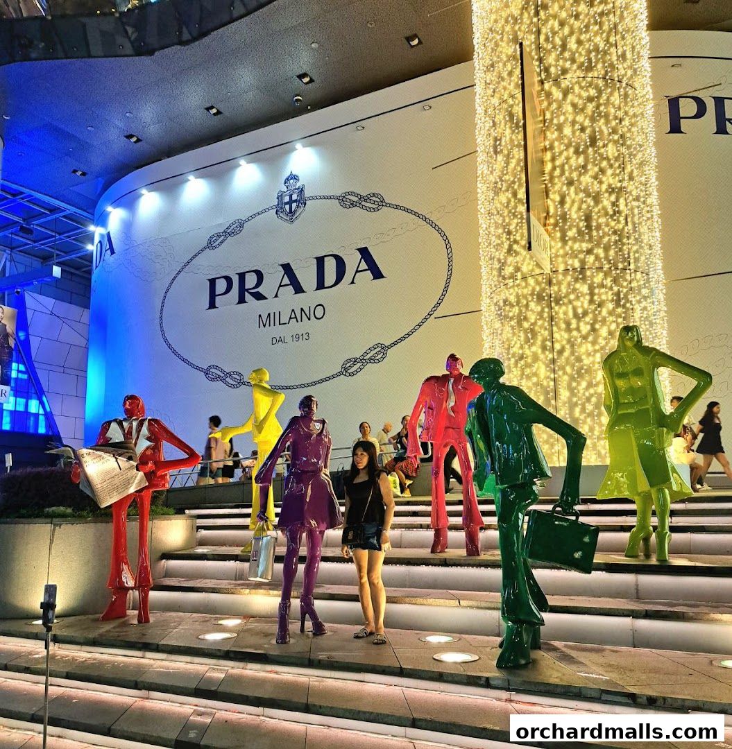 A woman poses with colorful sculptures in front of a Prada store facade.