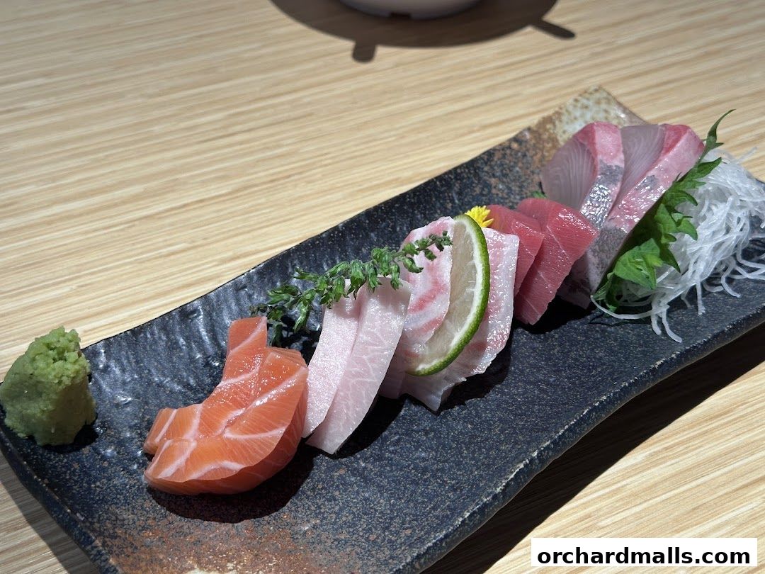 A plate of assorted sashimi with wasabi and garnishes on a wooden table.