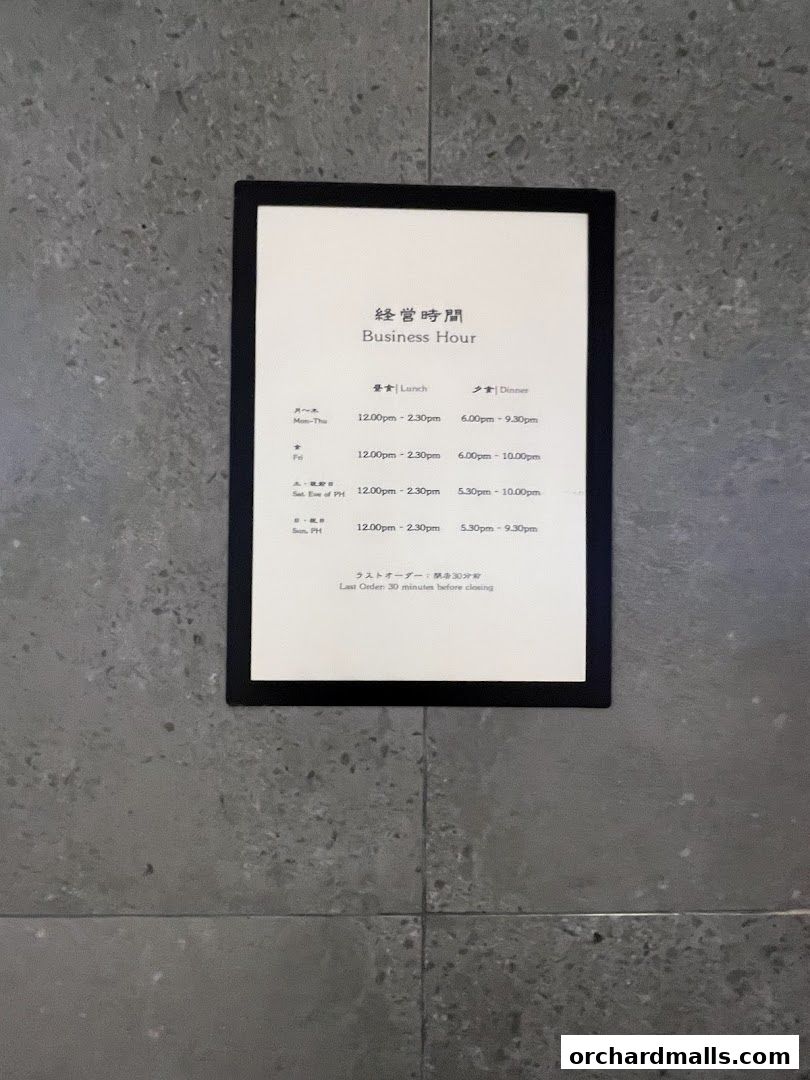 A sign displaying the business hours for UYA Unagi Singapore Wheelock.
