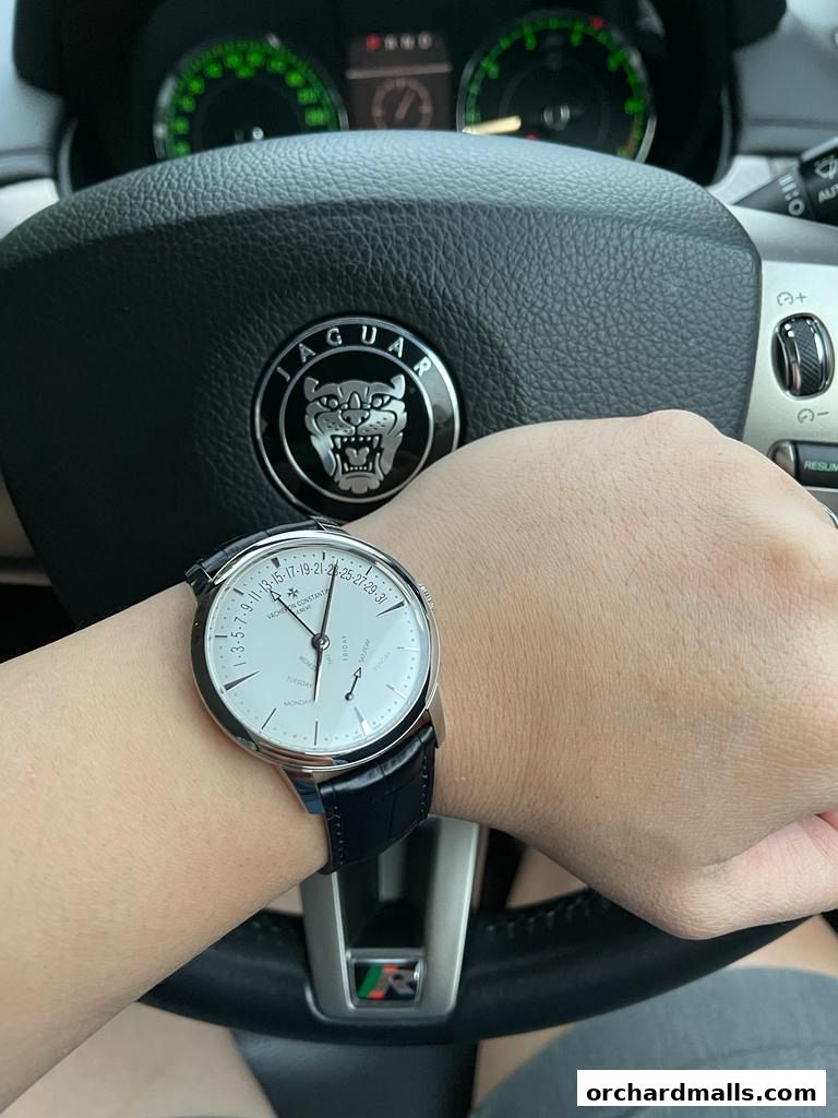 A person wearing a Vacheron Constantin watch while driving a Jaguar.