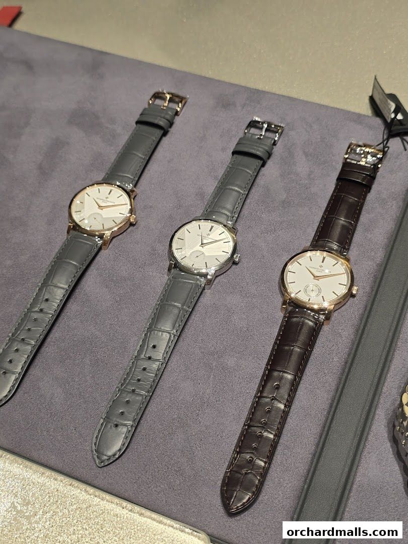 Three elegant Vacheron Constantin watches with leather straps displayed on a grey surface.