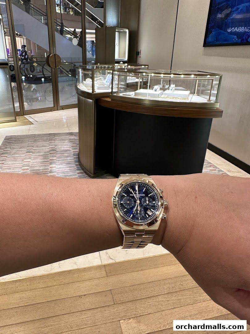 A person wearing a Vacheron Constantin watch in front of a display case.