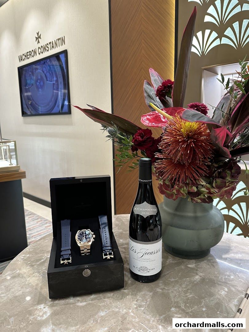 A Vacheron Constantin watch in its box with extra straps and a bottle of wine.