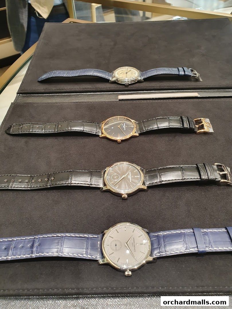 A display of four luxury Vacheron Constantin watches with leather straps on a dark velvet surface.