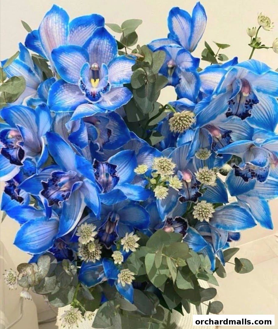 A vibrant bouquet of blue orchids with eucalyptus leaves and small white flowers.