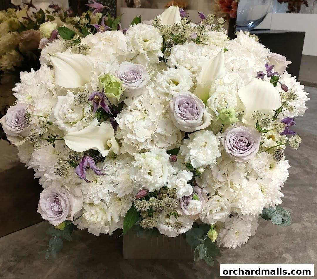 A large, elegant bouquet of white and lavender flowers with calla lilies and roses.