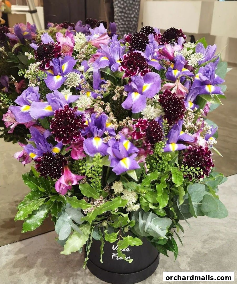 A vibrant bouquet of purple irises and other flowers in a black box.