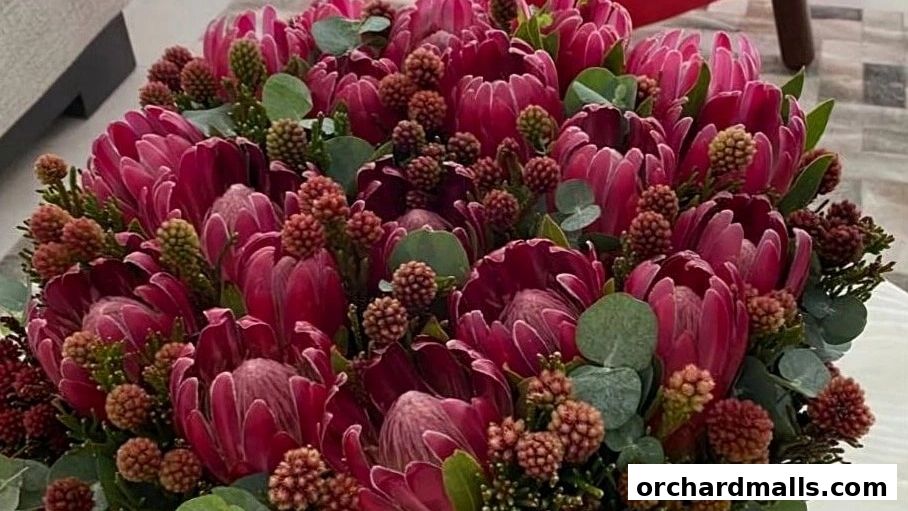 A close-up of a vibrant bouquet featuring deep pink protea flowers and small, textured buds.